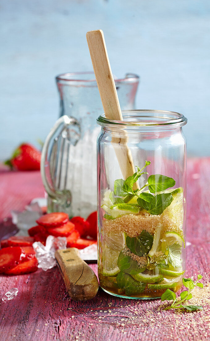 Non-alcoholic punch with strawberries, limes, mint and brown sugar being made