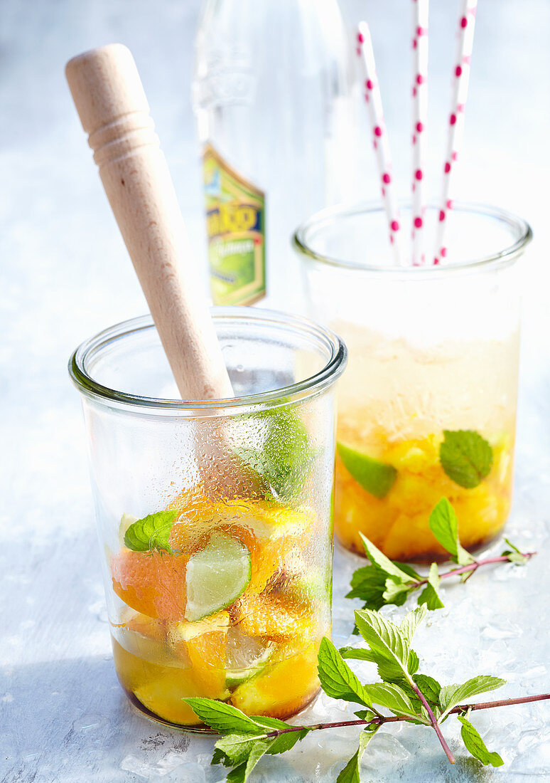 Orange and lime punch with cachaca and mint in jars