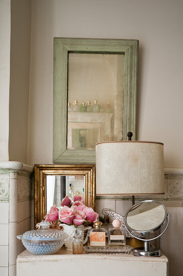 Verschiedene Spiegel, Parfums und Rosen im Badezimmer mit Shabby-Chic-Fliesen