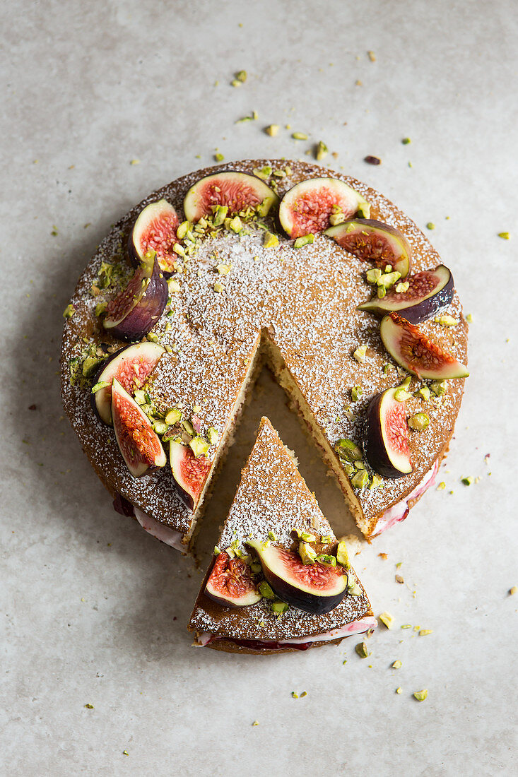 Victoria sponge cake deorated with figs, pistachio nuts and icing sugar