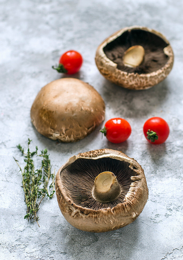 Raw portobello mushrooms, thyme sprigs and cherry tomatoes