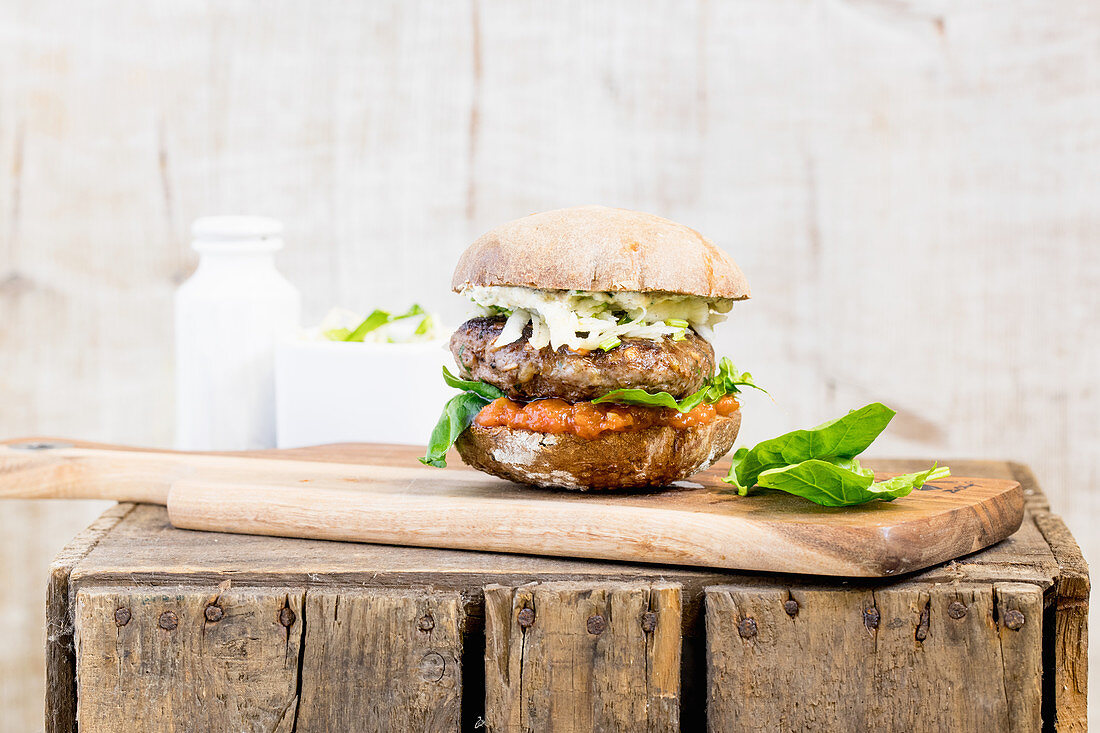A burger with coleslaw on a wooden board