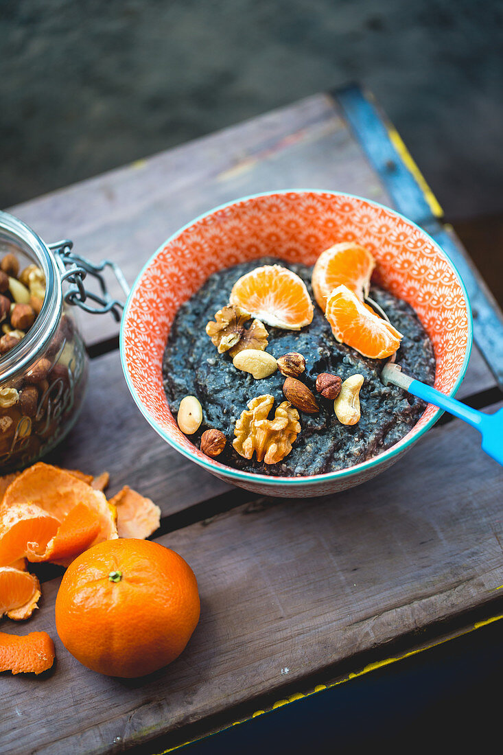 Charcoal oatmeal porridge with chia seeds, clementine and nuts