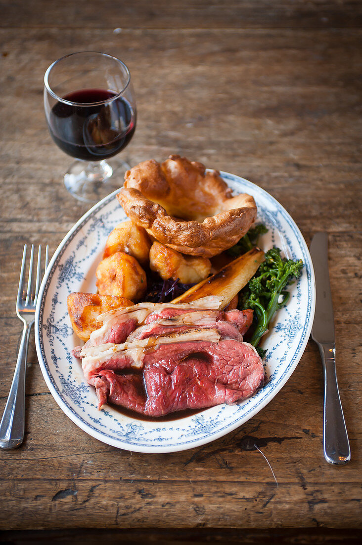 Roast Beef mit Yorkshire Pudding serviert mit einem Glas Rotwein