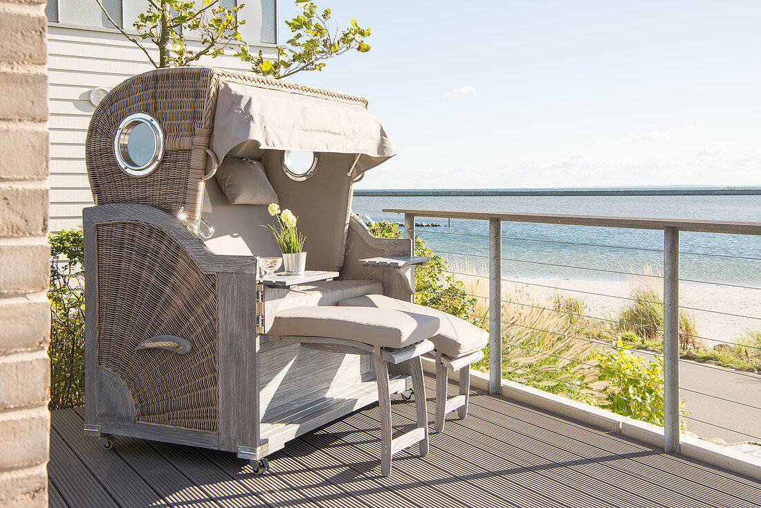 Wicker beach chair on wooden terrace with sea view