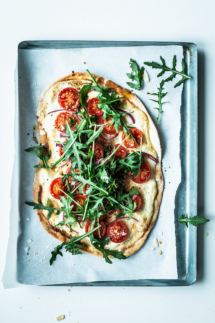 Tarte flambée with sour cream, tomatoes and rocket