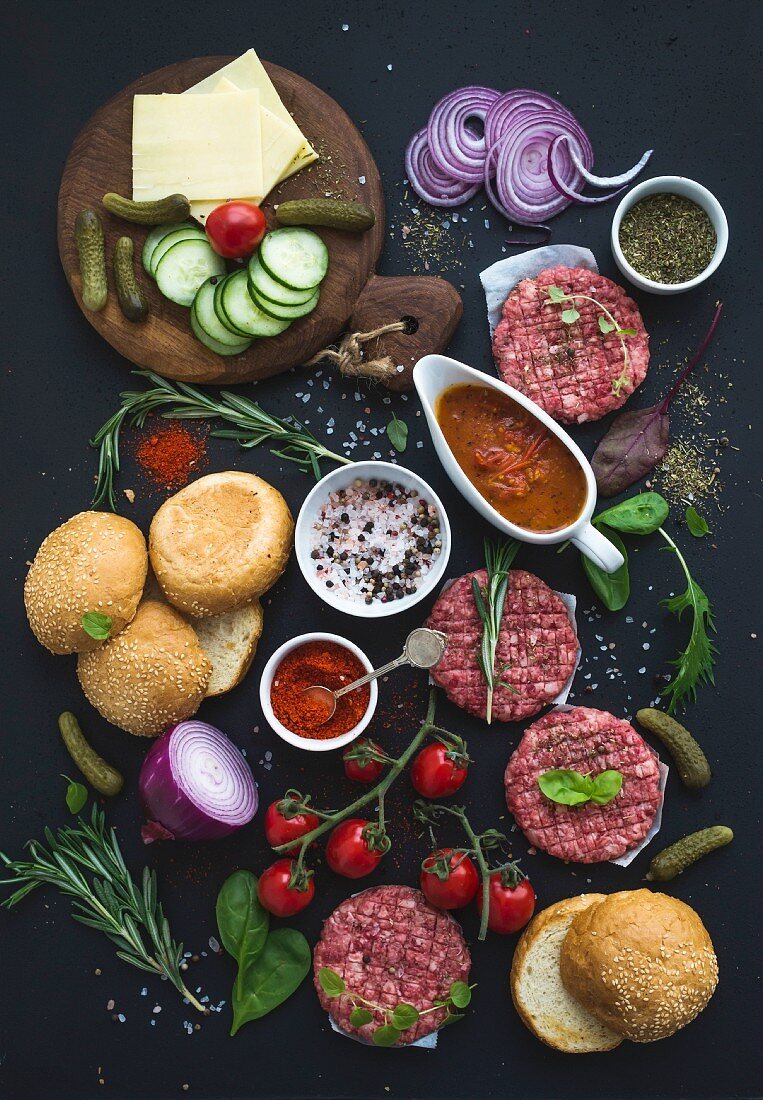 Zutaten für Burger: Brötchen, Patties, Gemüse und Tomatensauce