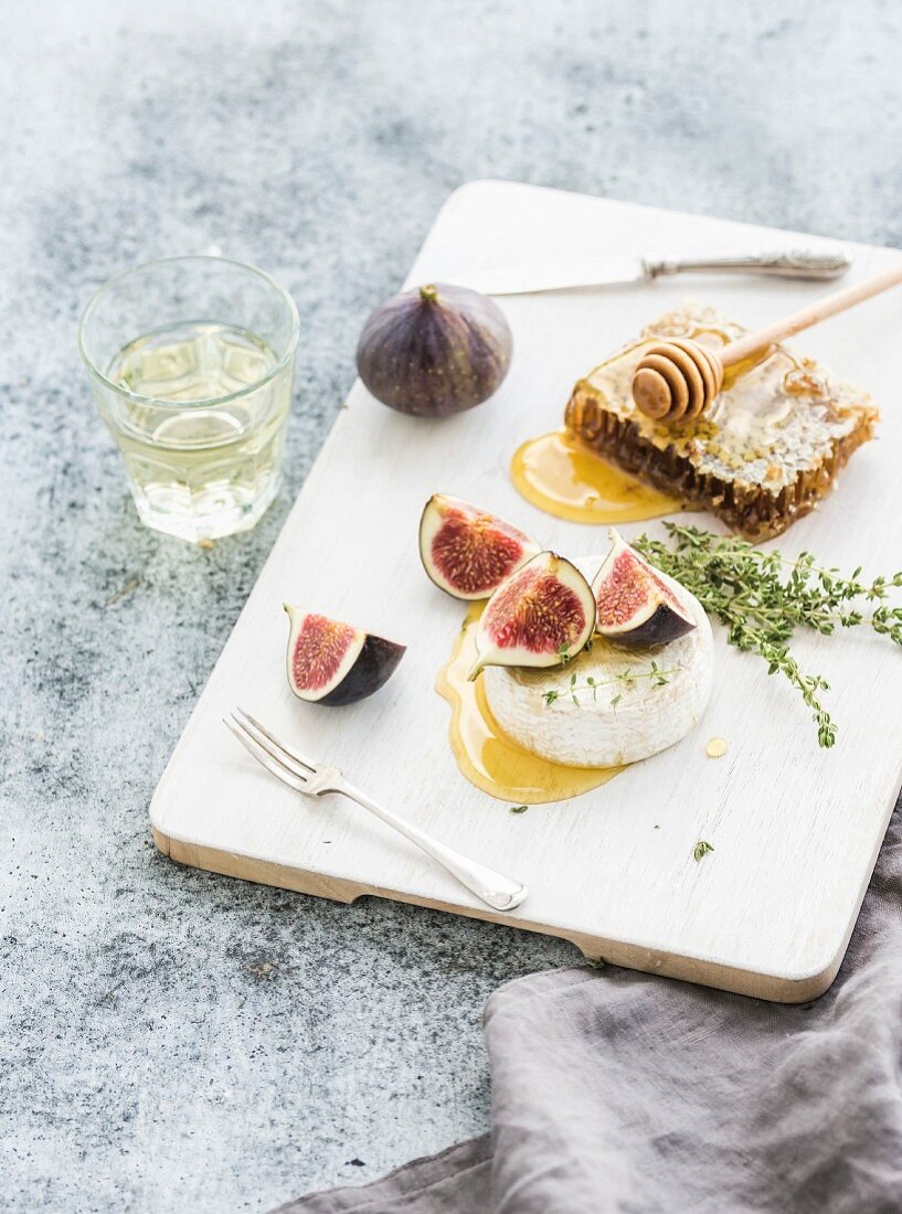 Camembert or brie cheese with fresh figs, honeycomb and glass of white wine