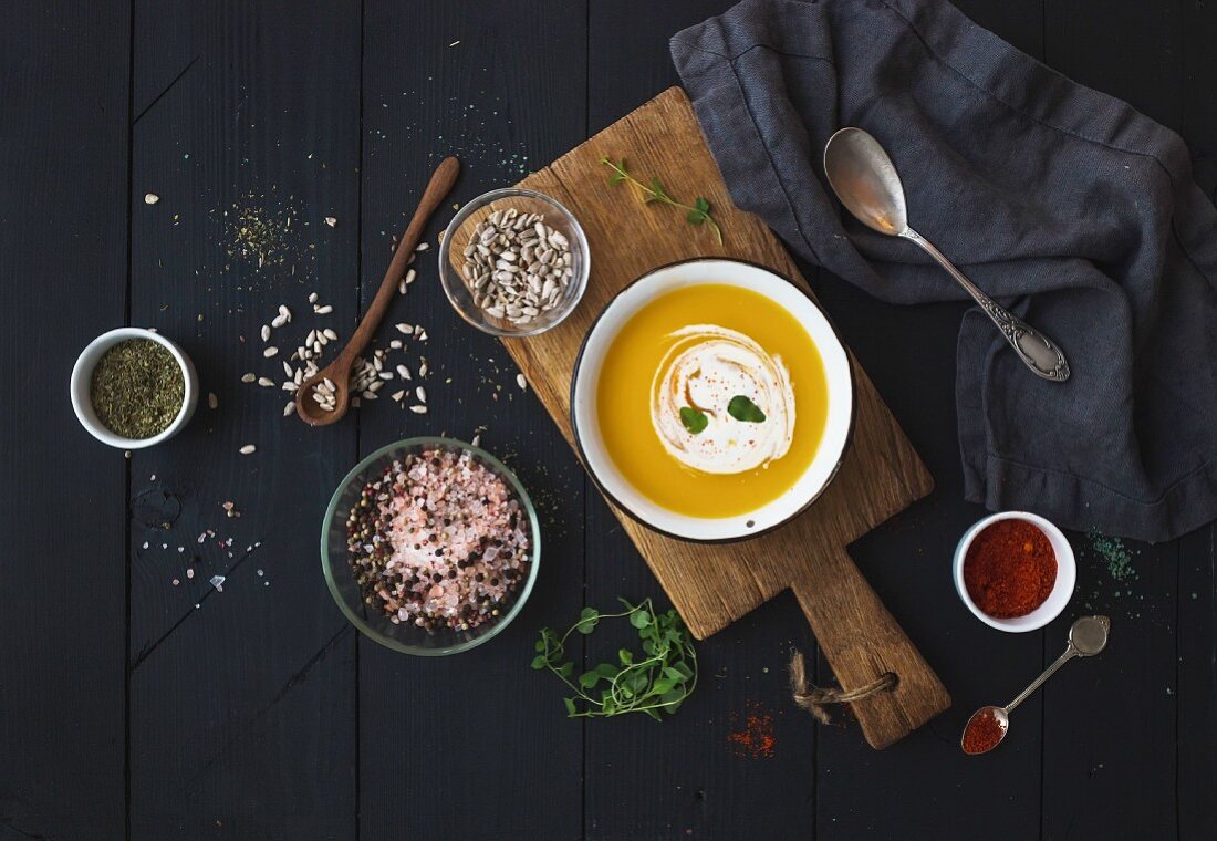 Pumpkin soup with cream, seeds and spices in rustic metal bowl