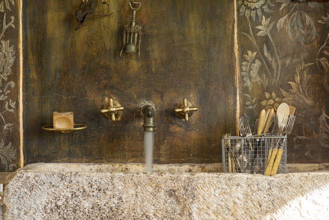 Vintage stone sink with brass wall-mounted taps in vintage surroundings