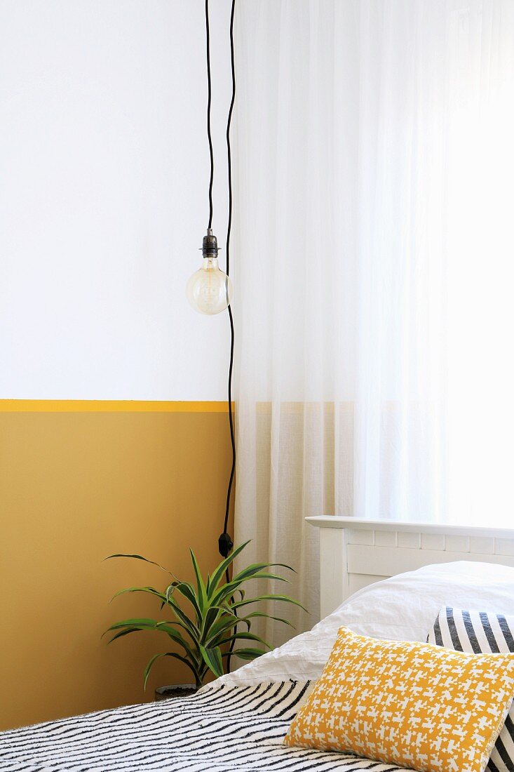 Light-bulb pendant lamp in front of wall with yellow dado