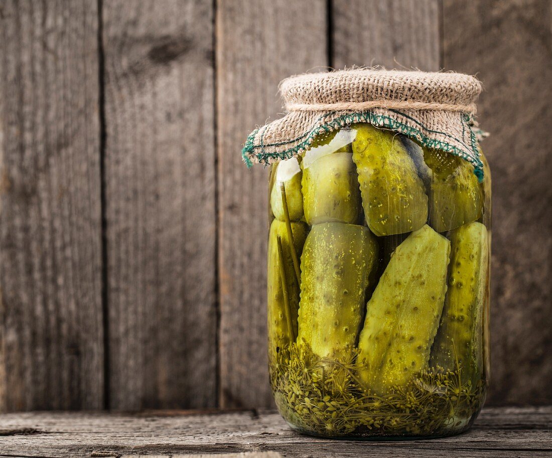 Jar of homemade pickles on a rustic wooden board