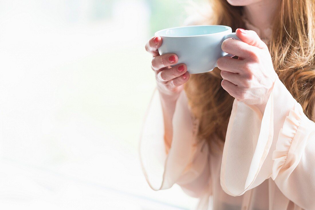 A woman holding a cup of coffee in a blue mug