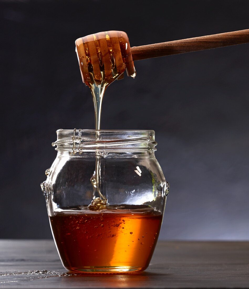 Honig mit Honiglöffel aus Glas heben