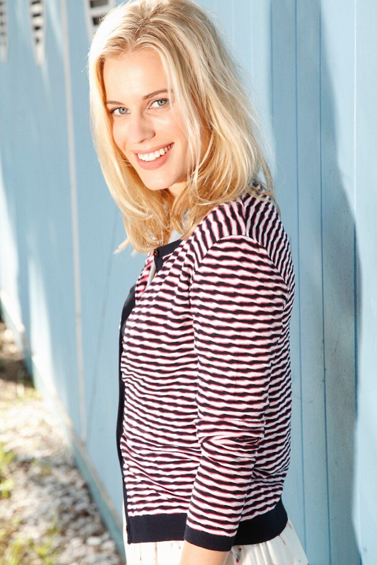A blonde woman wearing a white skirt and a striped cardigan