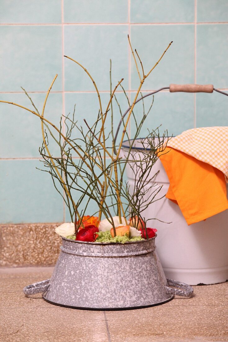 Flower arrangement in upturned enamel colander