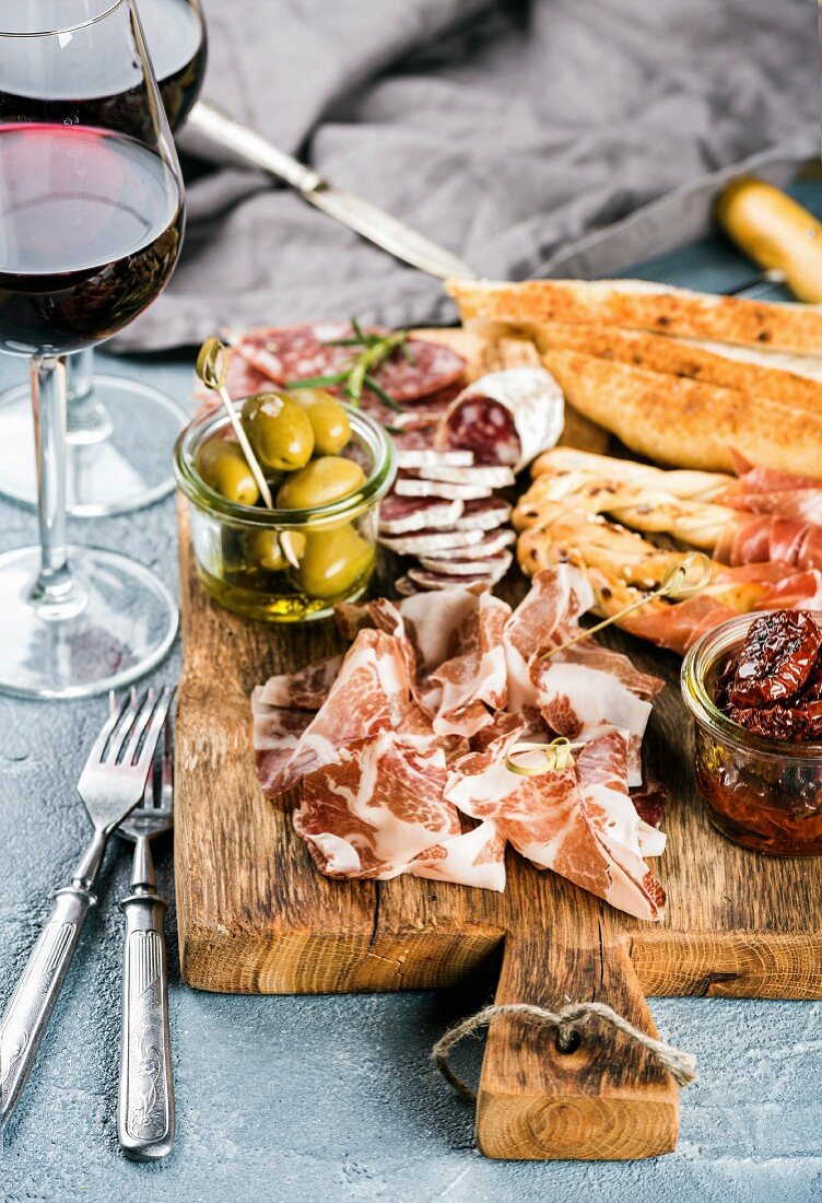 Meat appetizer selection: Salami, prosciutto, bread sticks, baguette, olives and sun-dried tomatoes