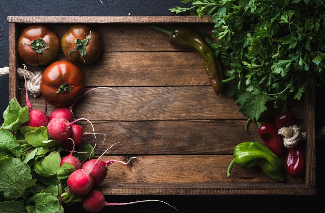 Frisches Gemüse: Radieschen, Tomaten, Petersilie und Paprikaschoten in einer Holzkiste