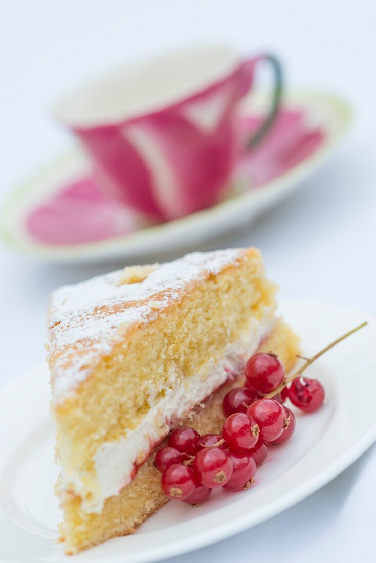 Ein Stück Victoria Sponge Cake mit roten Johannisbeeren