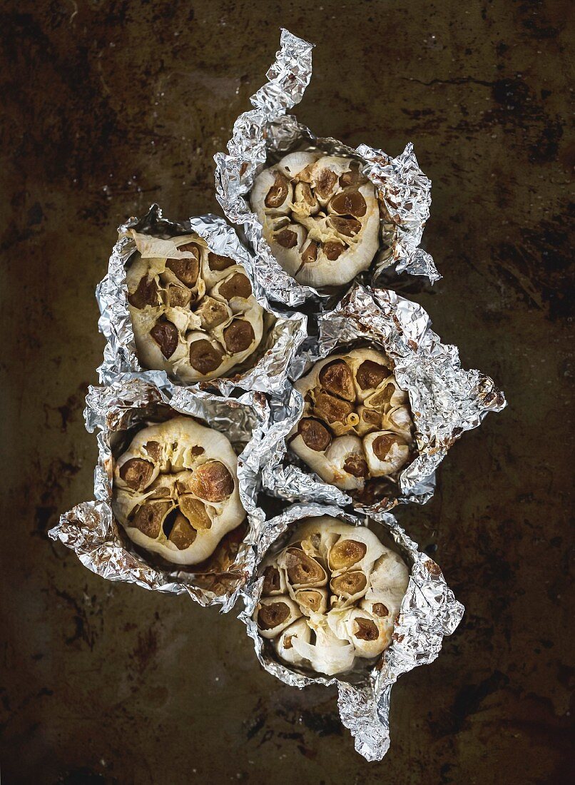 Oven-Roasted Garlic bulbs are displayed on a dark background