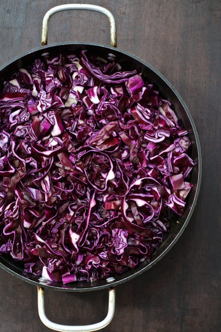 Shredded red cabbage in a pan on wooden table