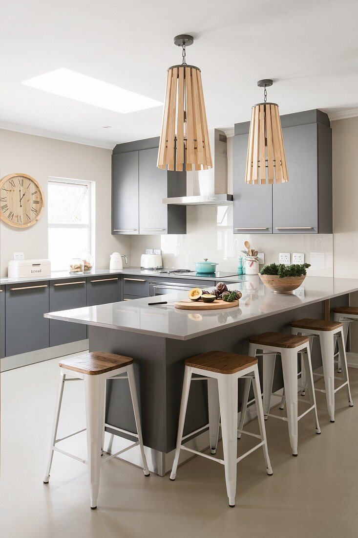 U-shaped kitchen with island counter and grey doors in open-plan interior