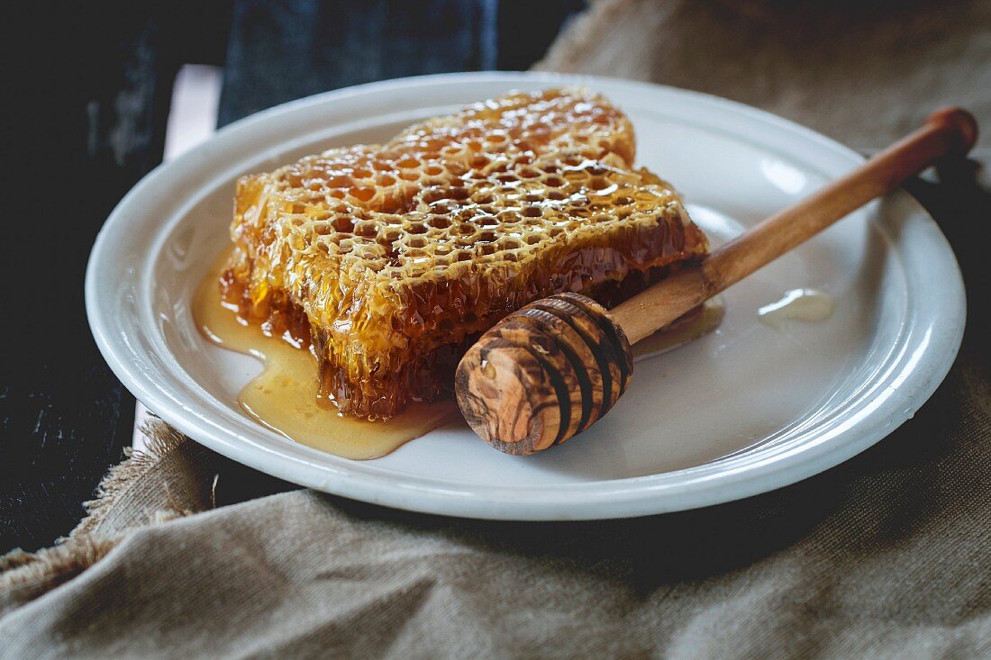 Honigwabe mit Honiglöffel auf Keramikteller