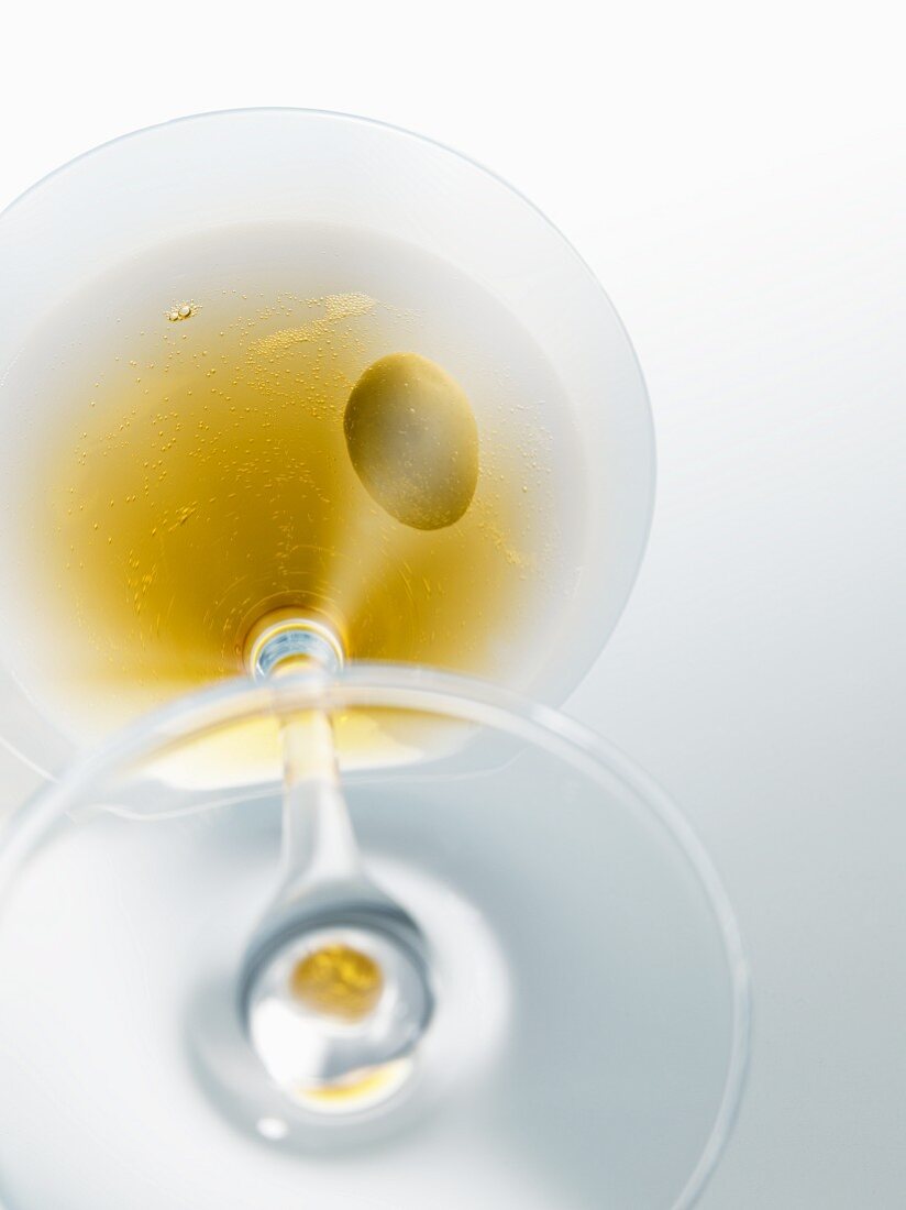 A martini with an olive in a glass (view from below)