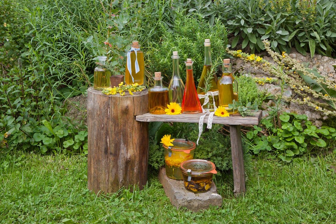 Verschiedene selbstgemachte Ölsorten auf Holztisch im Bauerngarten