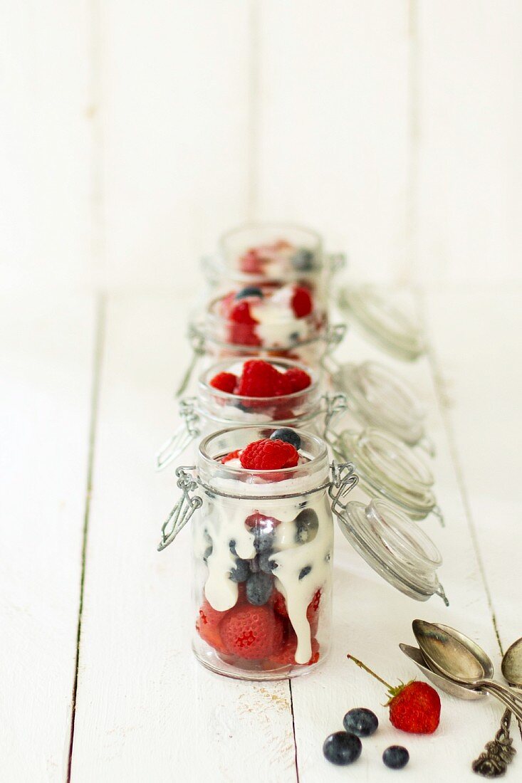 Fresh berries with vanilla sauce served in glass bottles