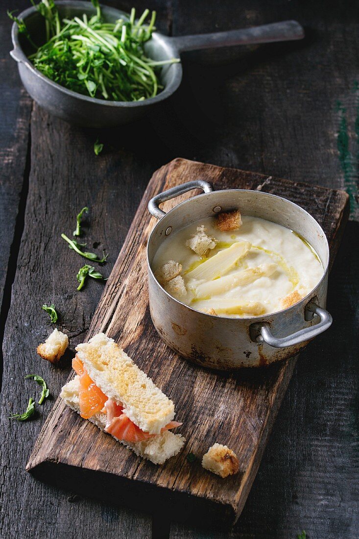 Vintage aluminum pan with white asparagus cream soup with pea sprouts, salted salmon and toast