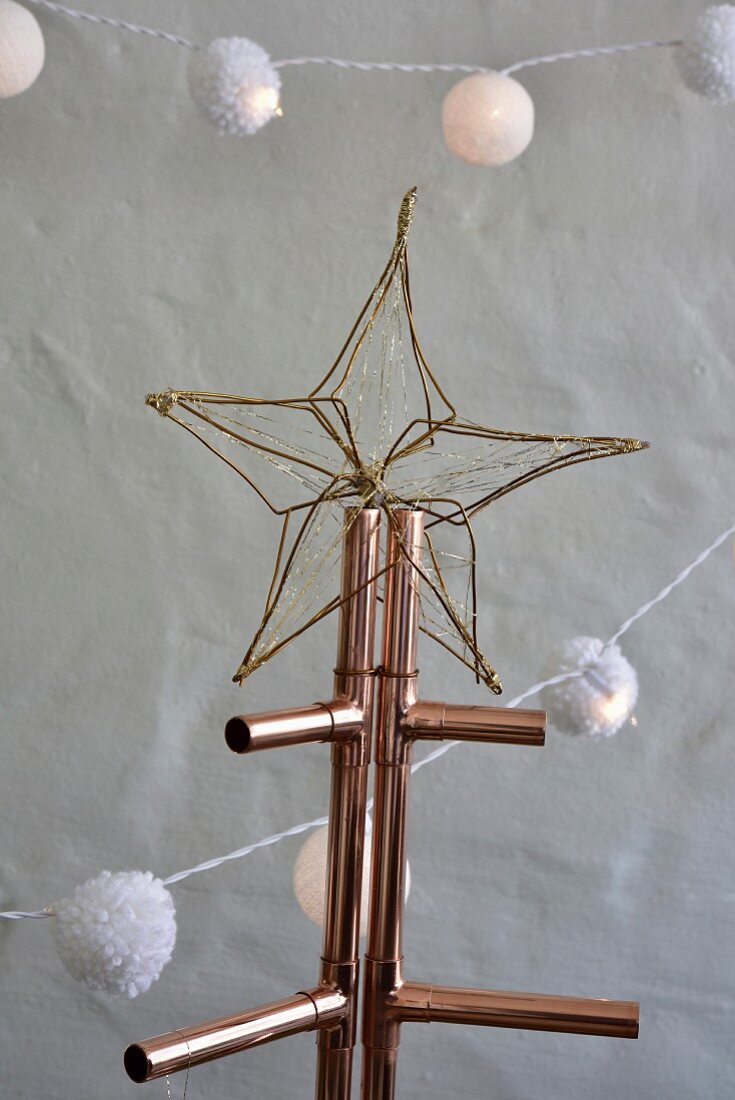 Golden wire star on Christmas tree made from copper piping