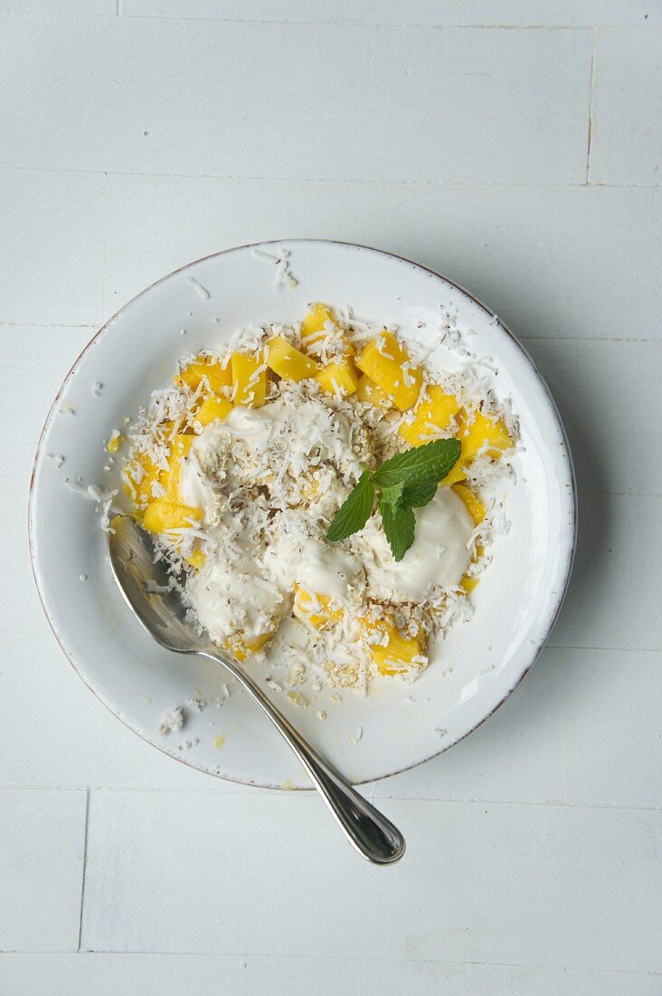 Muesli with oatmeal, coconut cream, dessicated coconut, mango and lemon balm