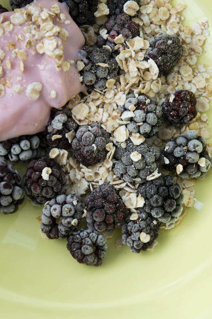 Muesli with oatmeal, frozen blackberries and yoghurt made from coconut milk