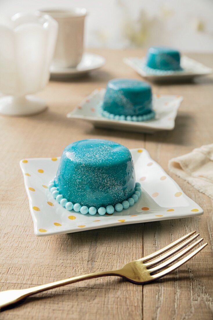Petit four cakes with aqua mirror glaze, glitter and dragees