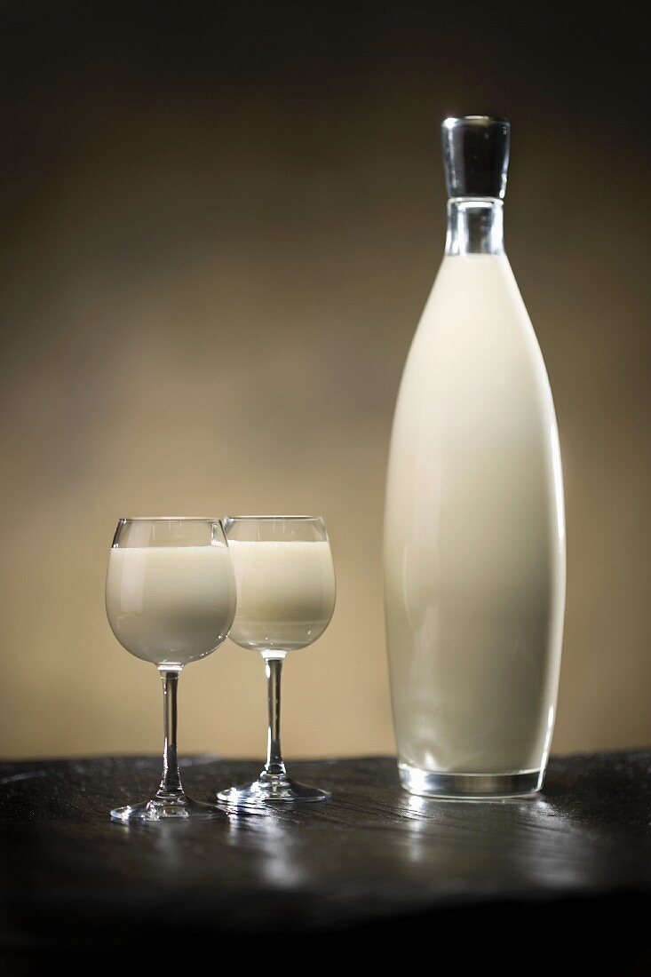 Bottled white russion cocktail with two galles on slate surface and golden background