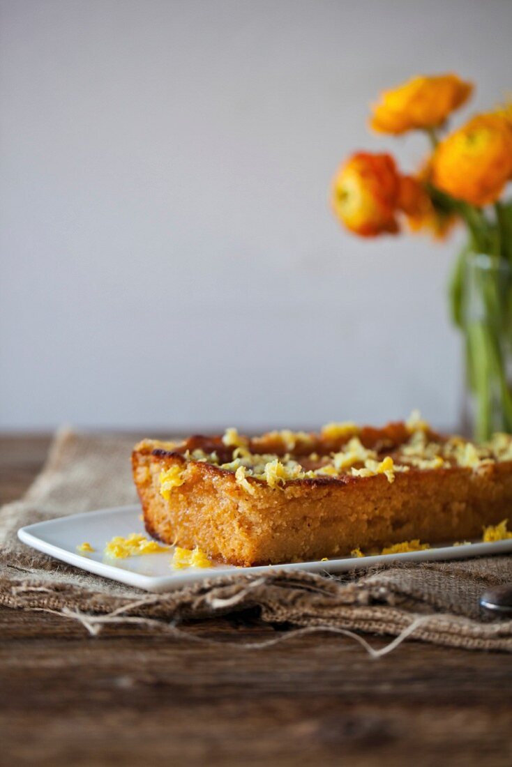 Lemon and olive oil cake on a white plate and rustic wooden table