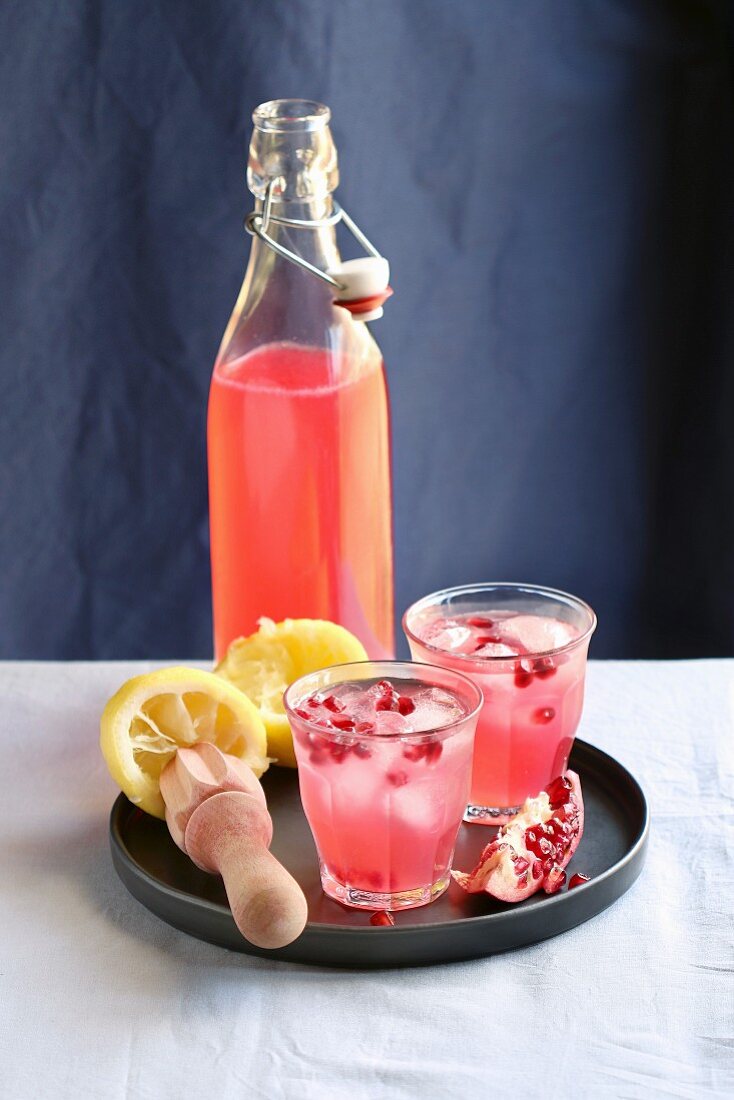Two glasses and a bottle with pomegranate lemonade