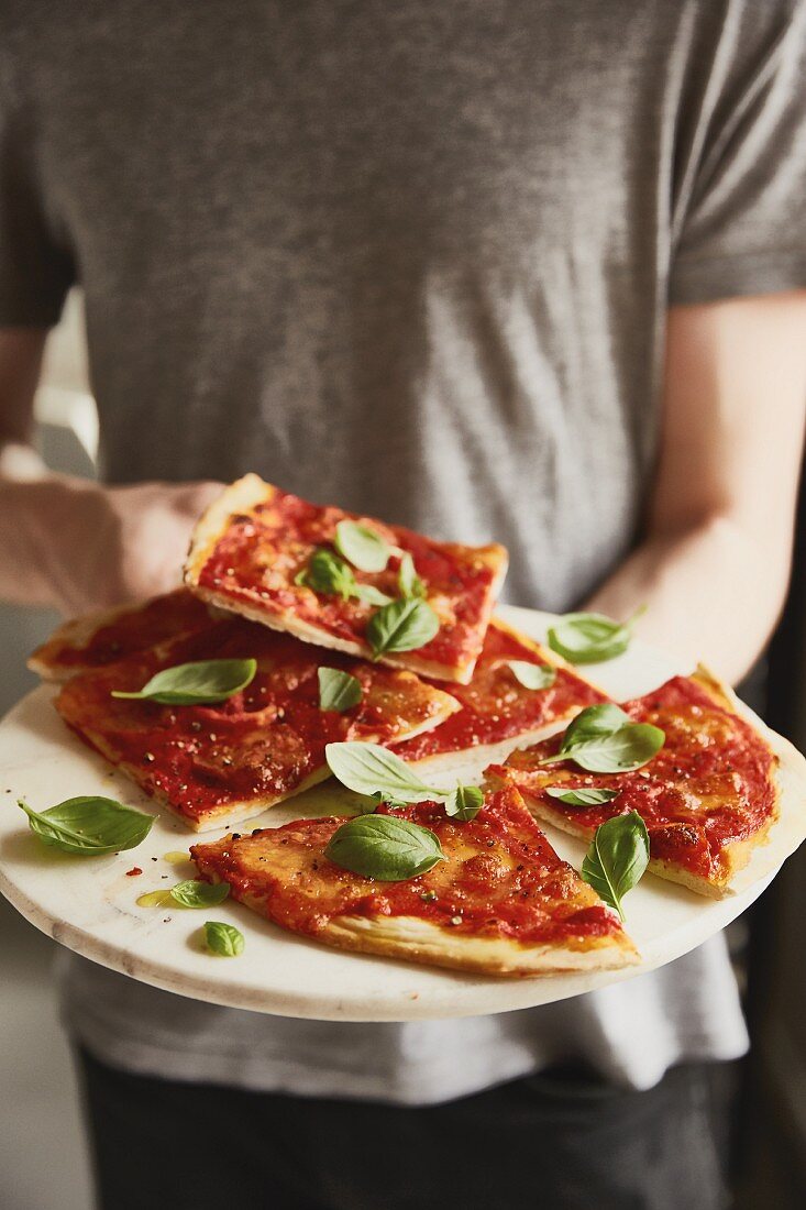 A man offering slices of pizza margherita