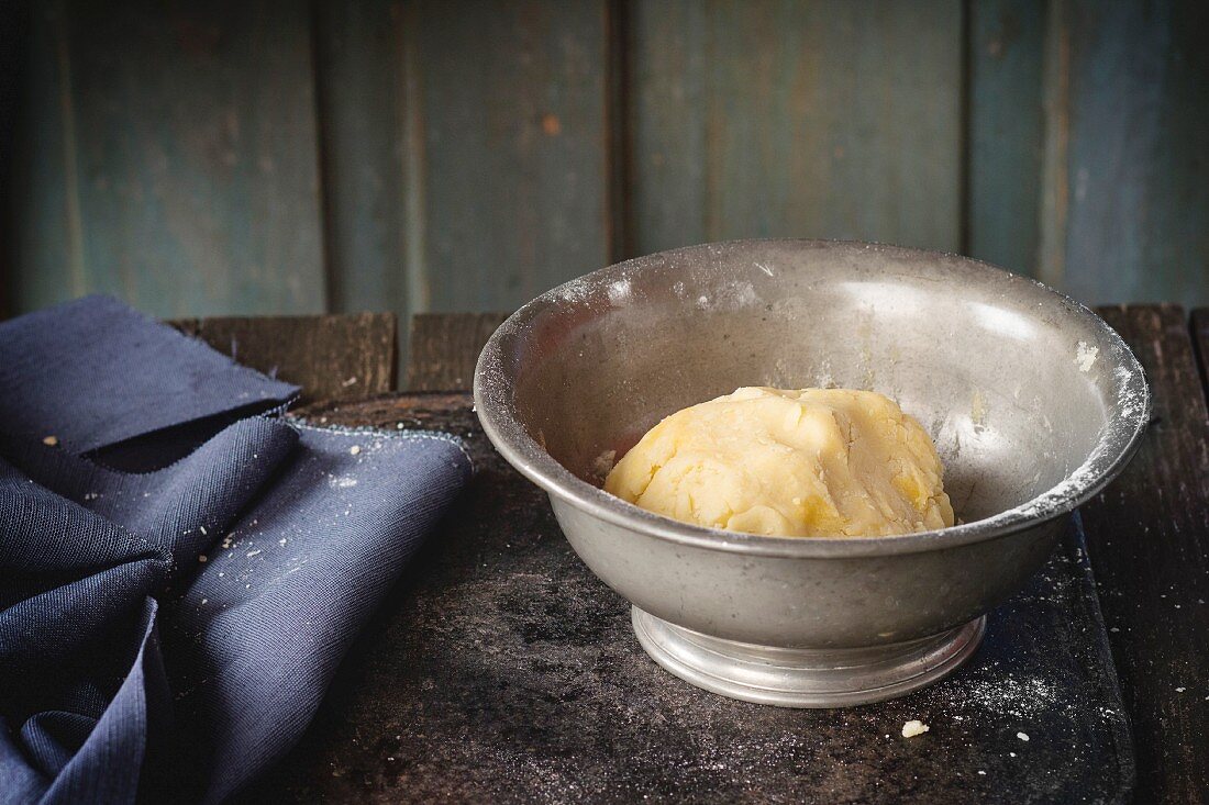 Shortcrust pastry dough in vintage metal bowl over old wooden table