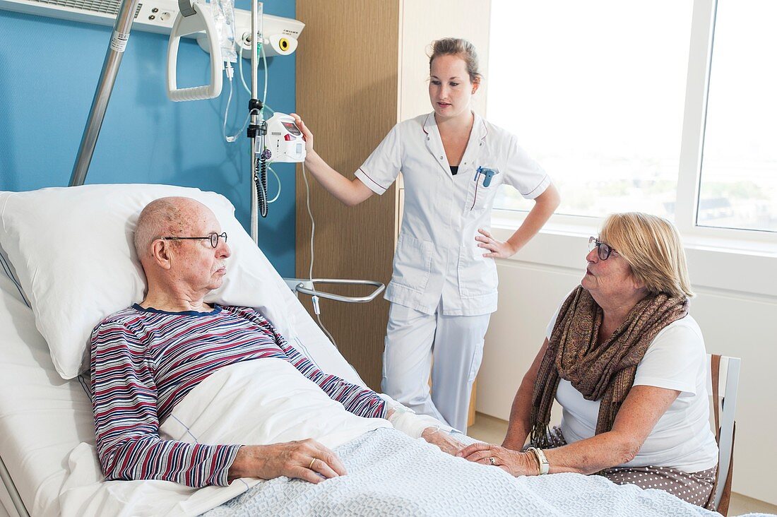 Woman visiting senior man , nurse listening