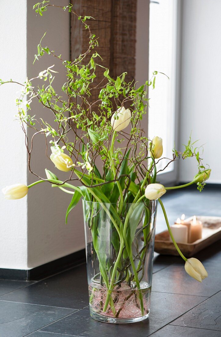 Tulpenstrauss in Glasvase auf dem Boden