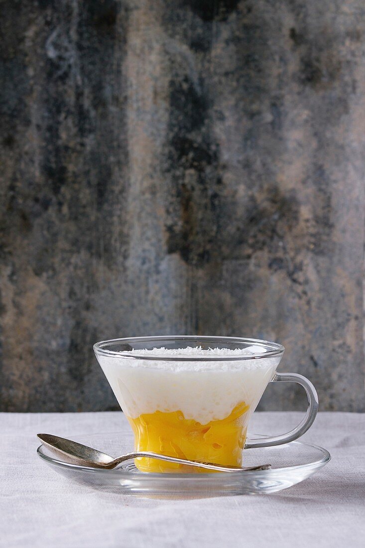 Gesunde Tapioka-Pudding mit Kokosmilch und Mango in einer Glastasse
