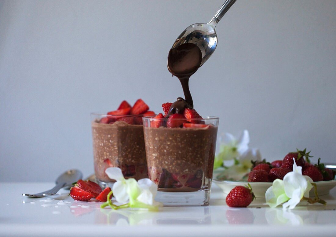 Vegane Overnight Oats mit Schokolade und Erdbeeren in Gläsern, mit geschmolzener Schokolade beträufeln