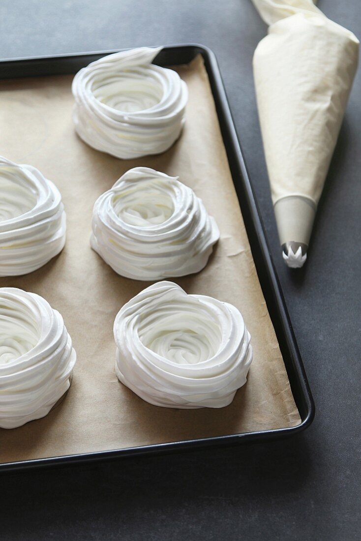 Meringue nests before baking on a tray lined with parchment paper