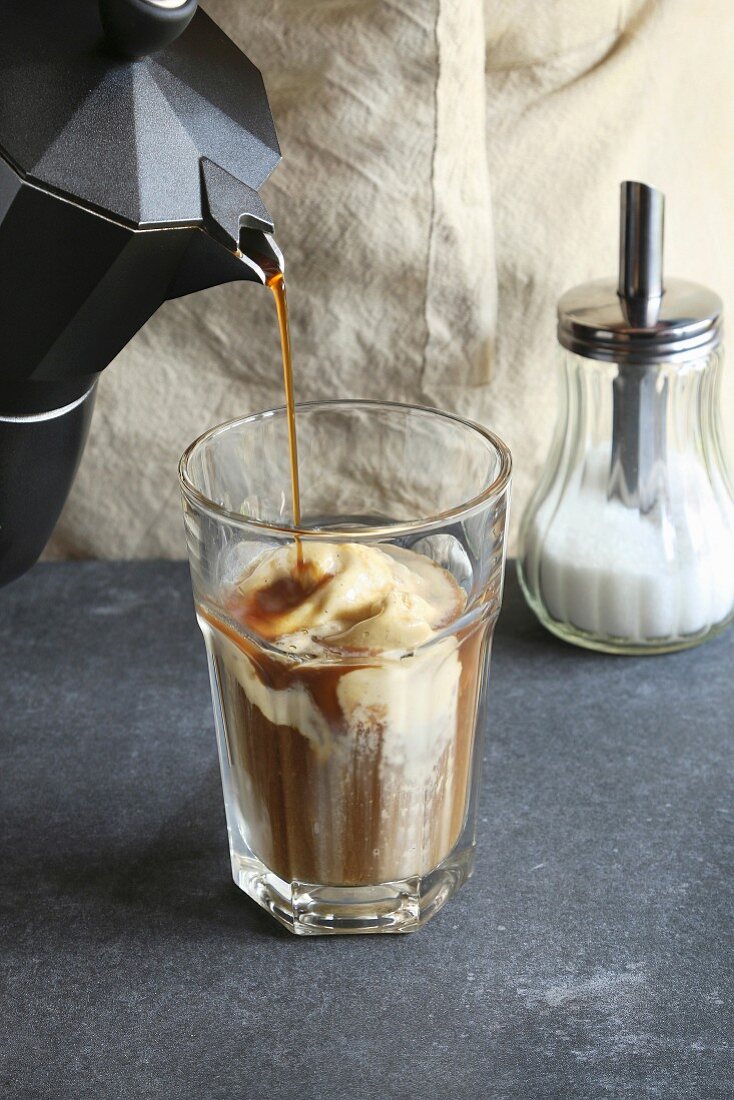 Kaffee wird in Glas mit Vanilleeis gegossen
