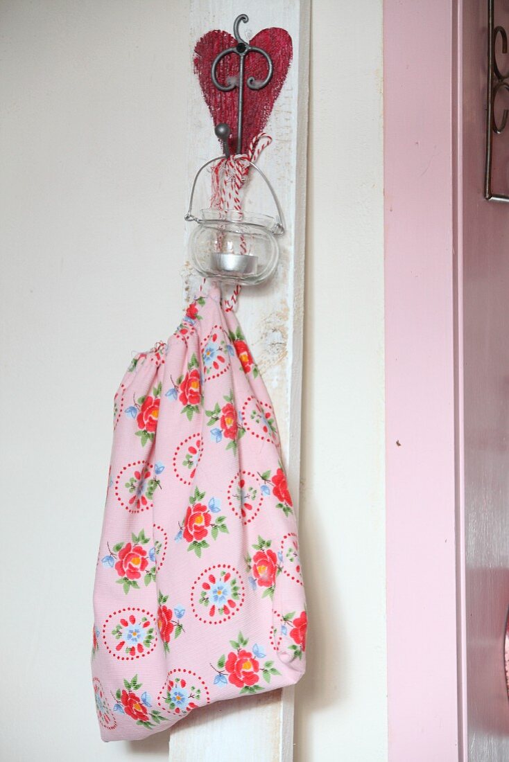 Fabric bag and tealight holder hung on white wooden batten with love-heart