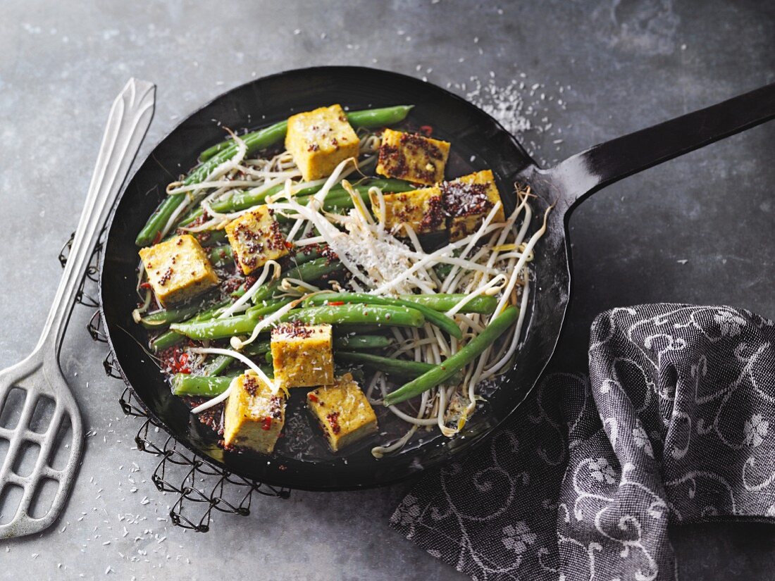 Vegan runner bean dish with mango and curry tofu and bean sprouts, served in a pan