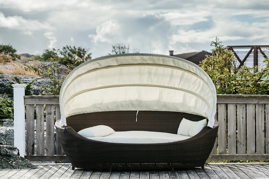 Ovale Loungeliege mit Sonnensegel auf einer Veranda