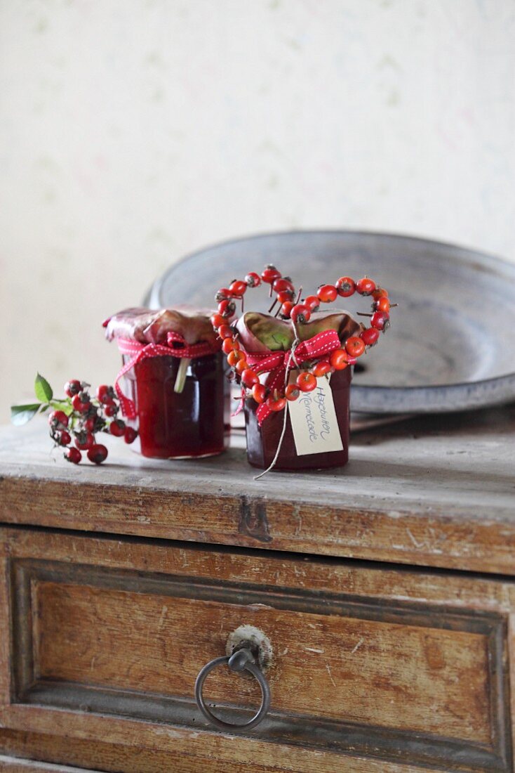 Marmeladeglas mit Hagebuttenherz dekoriert auf Vintage Kommode